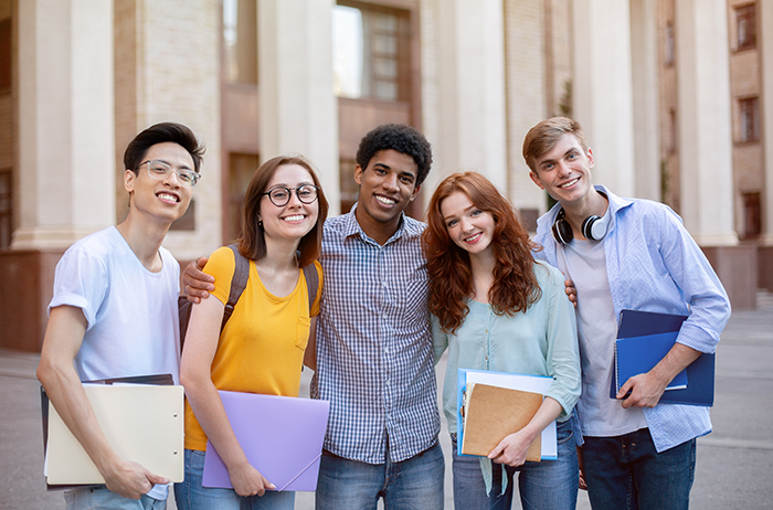 Happy Diverse Students Standing Together Near University Building Outdoors